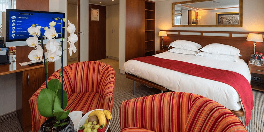 A Category Suite room, featuring a double bed, 2 club chairs and a desk.
