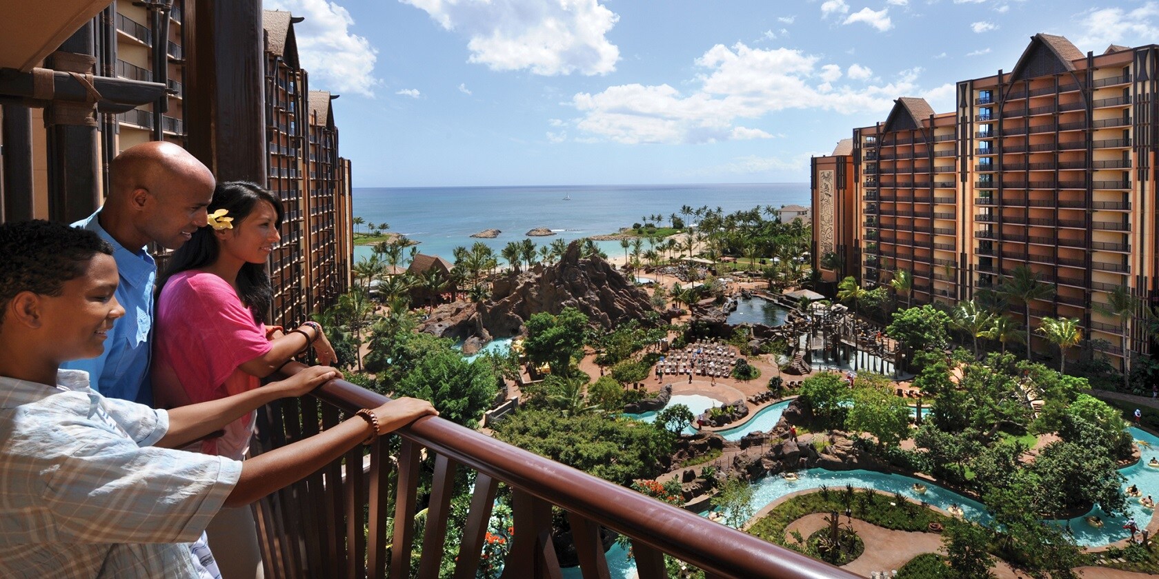 A boy and his parents looking over a balcony at the Aulani Resort pool area