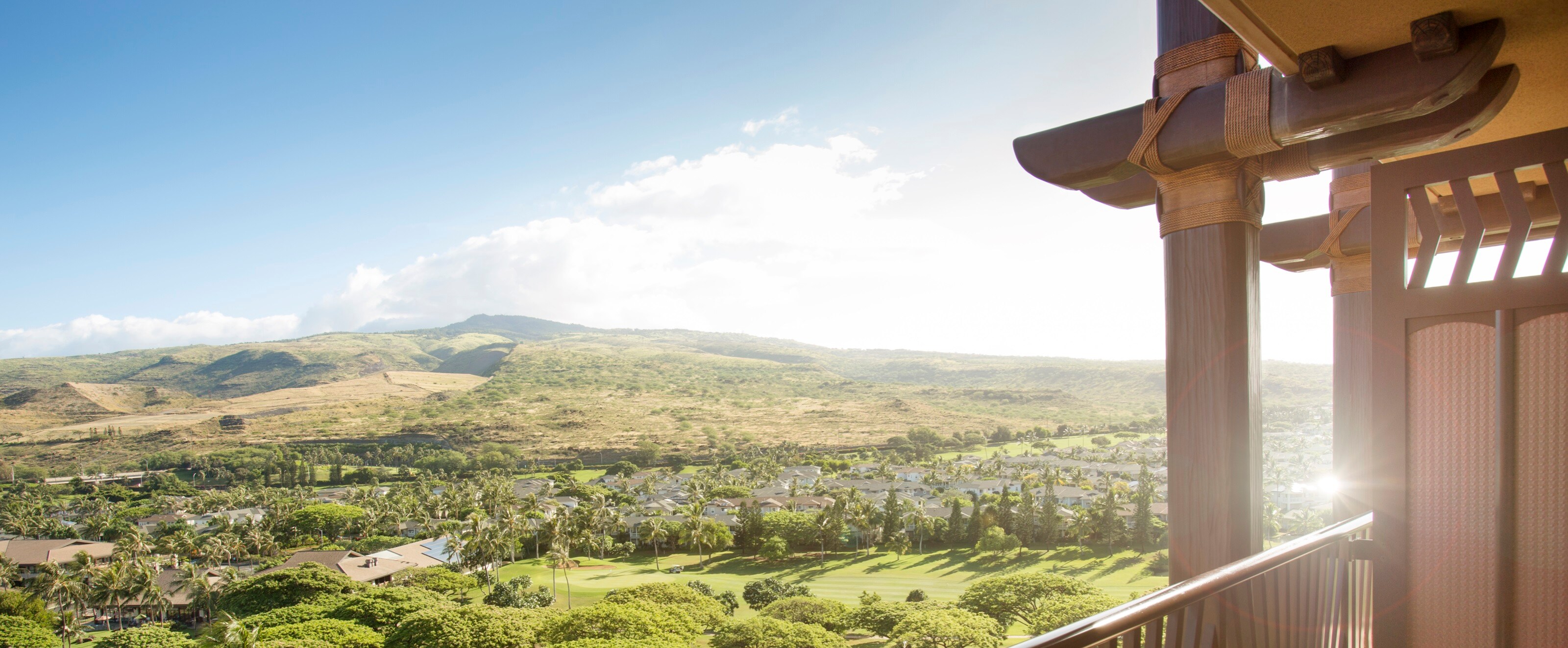 A balcony with a view of a forest, buildings and hills