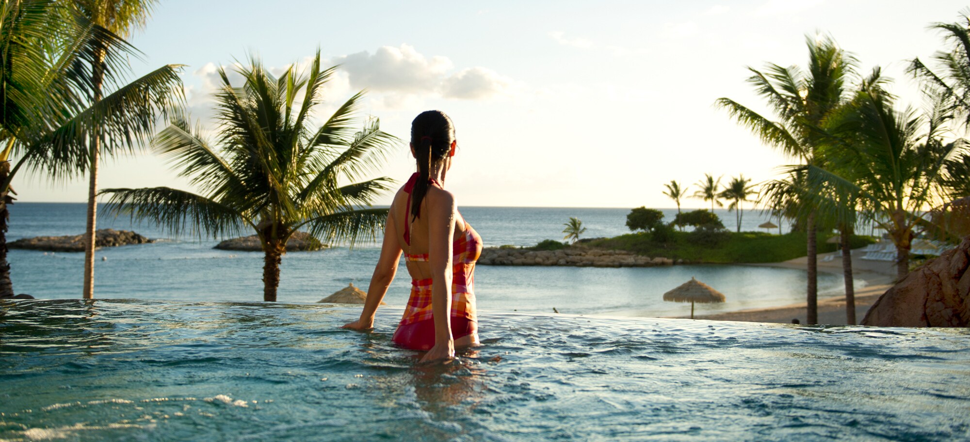 A bathing suit-clad female guest enjoys a whirlpool spa while gazing at the clouds above the ocean