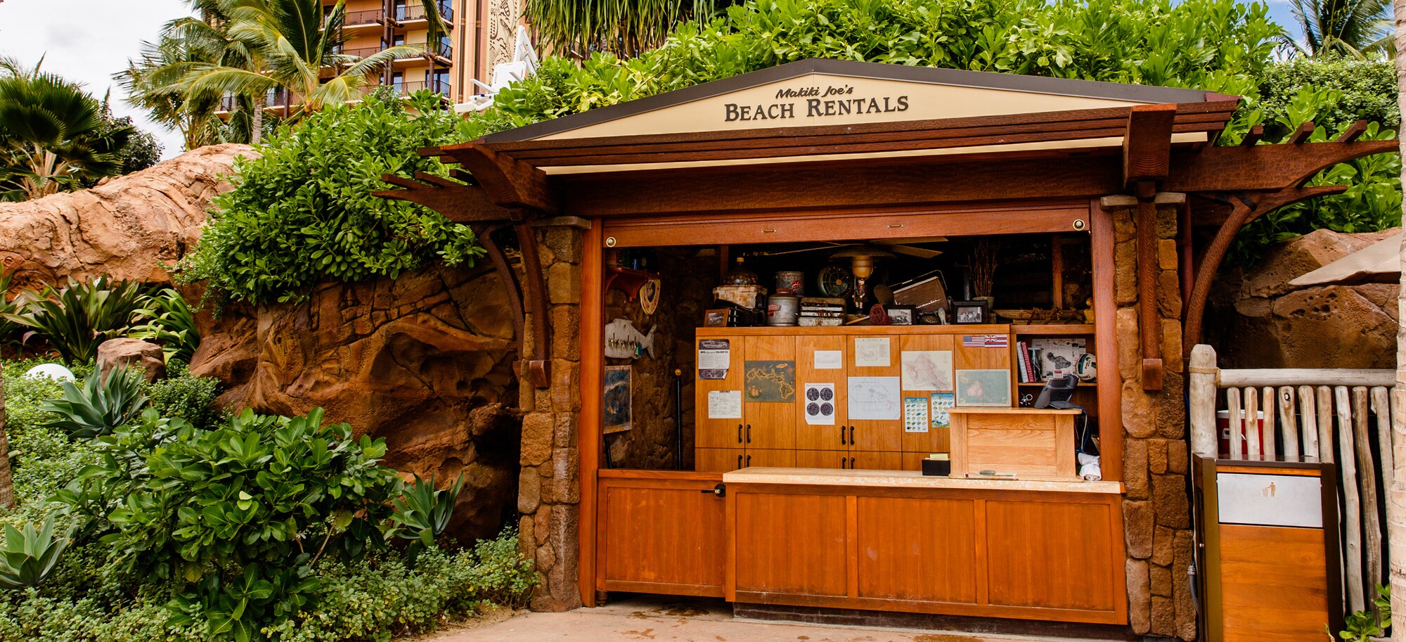 The exterior of Makiki Joe's Beach Rentals, a wooden shack nestled in trees and shrubbery