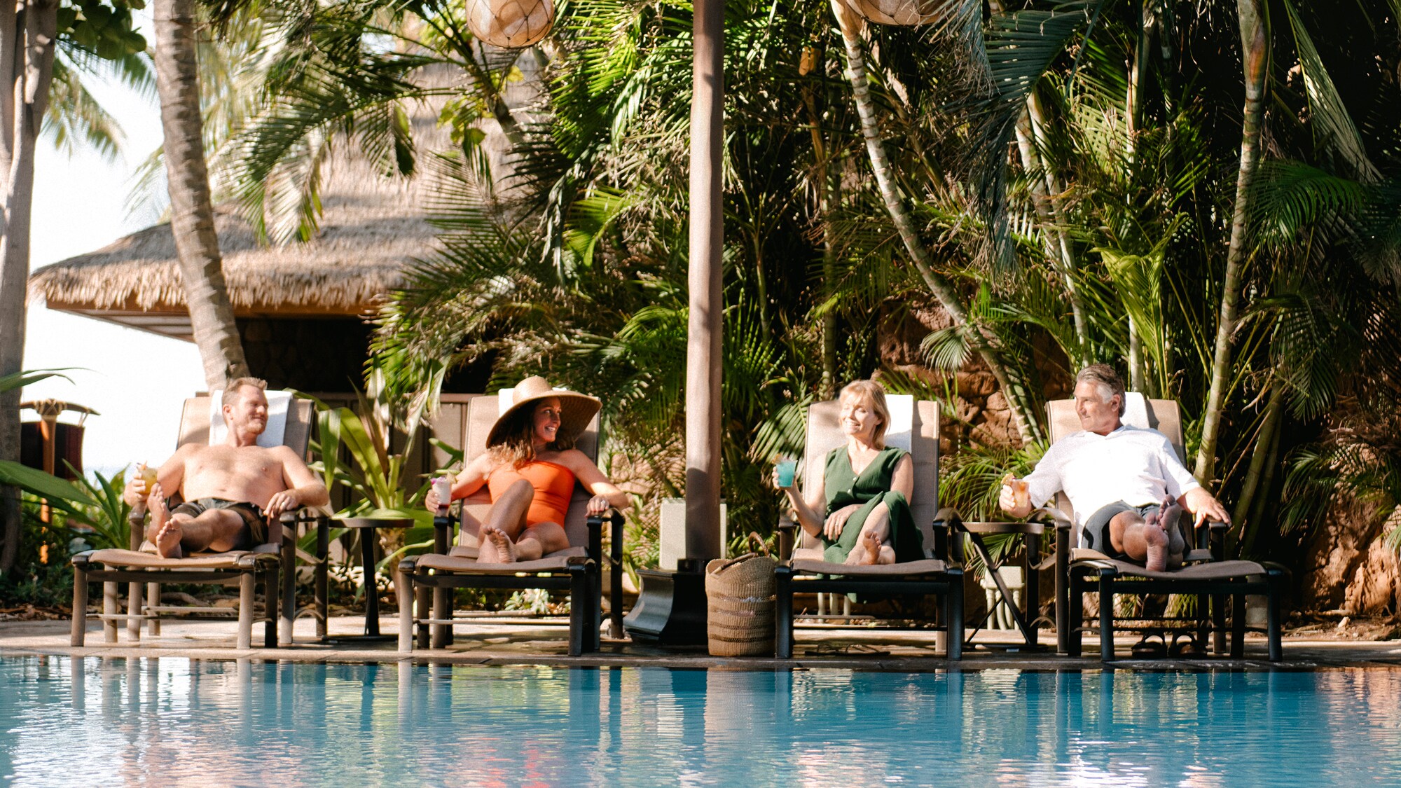 4 Guests lounging in pool chairs alongside a pool at Aulani, A Disney Resort and Spa