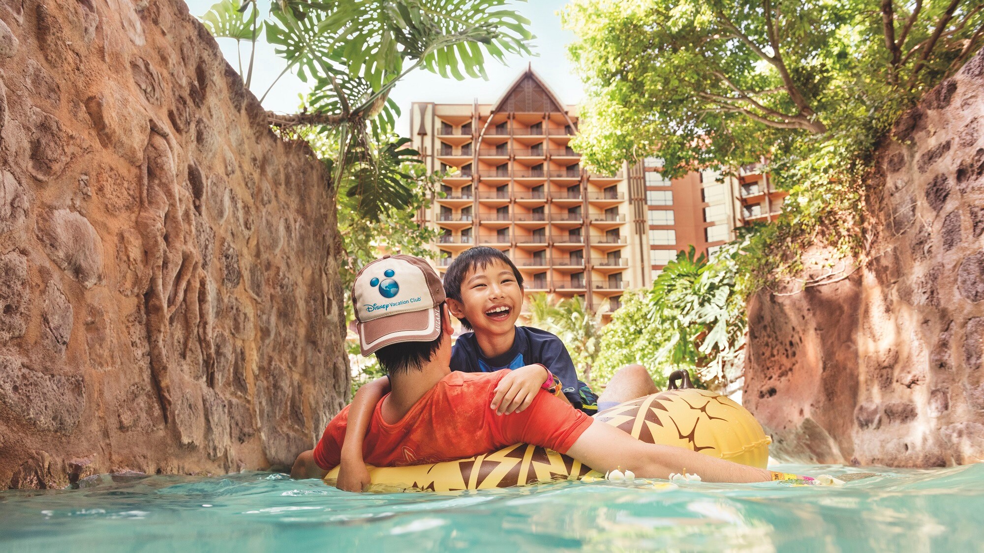 A father and son floating on a raft along the lazy river at Aulani Resort