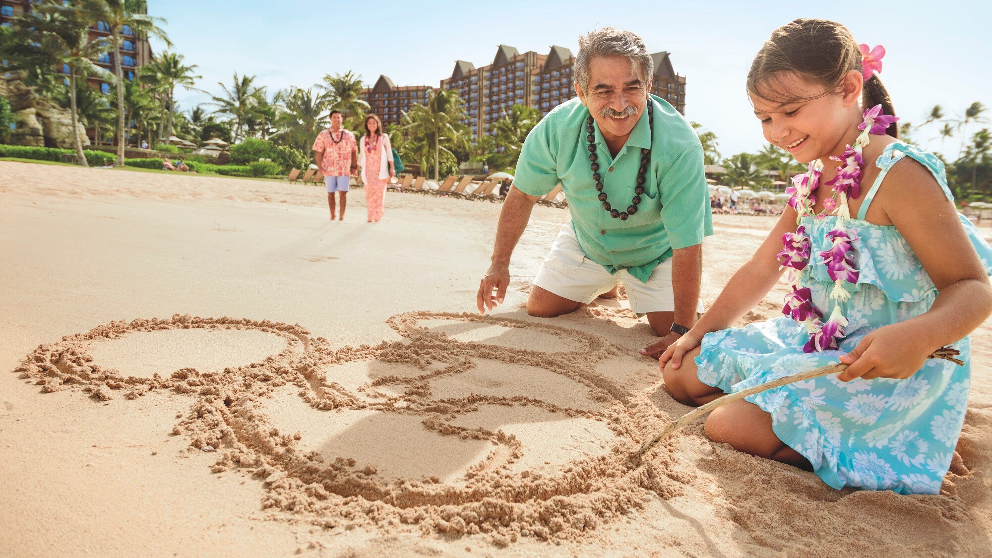 A girl and her grandfather drawing in the sand on the beach at Aulani Resort