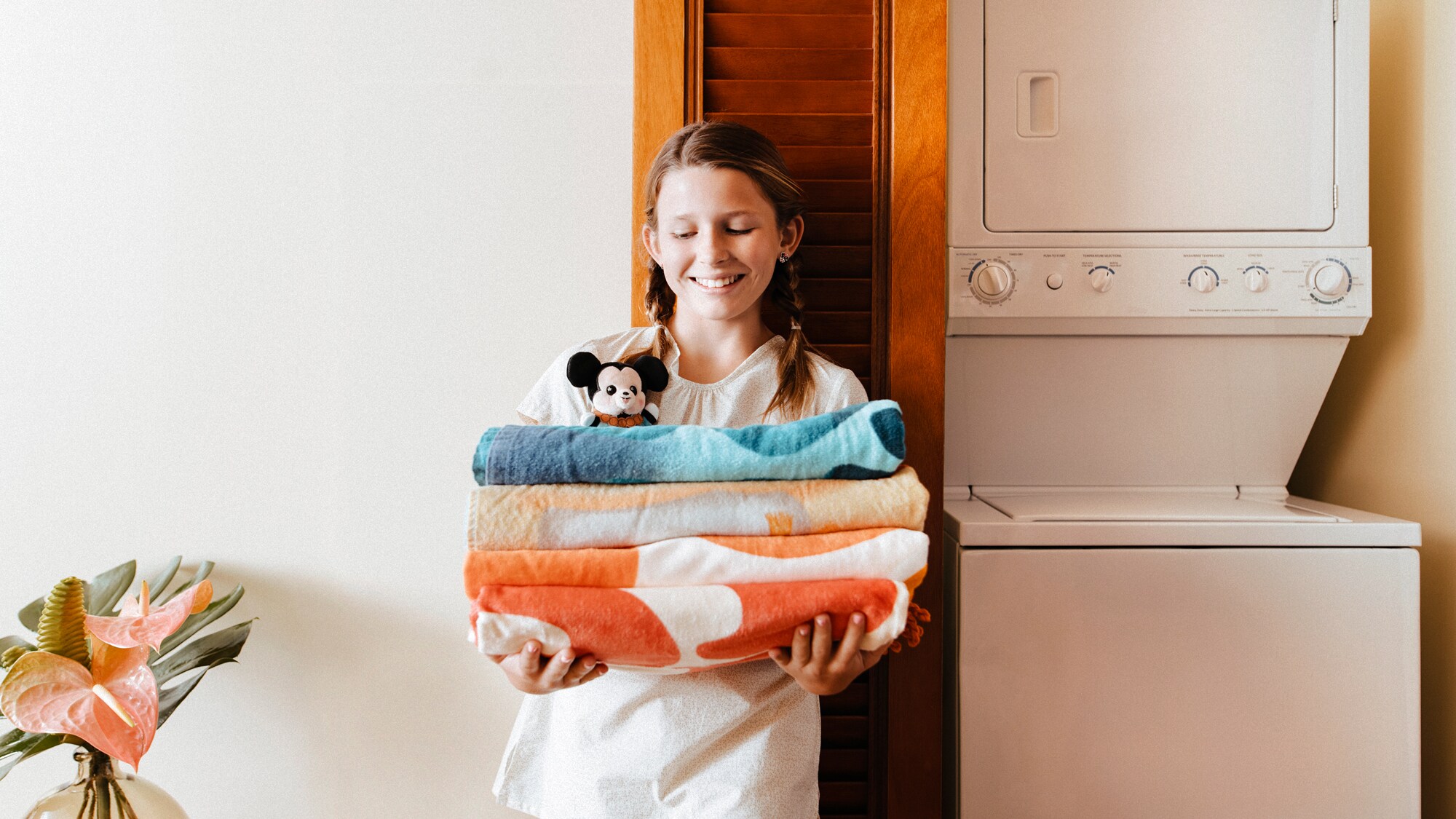 A young girl holding a stack of towels in the laundry area of a Villa