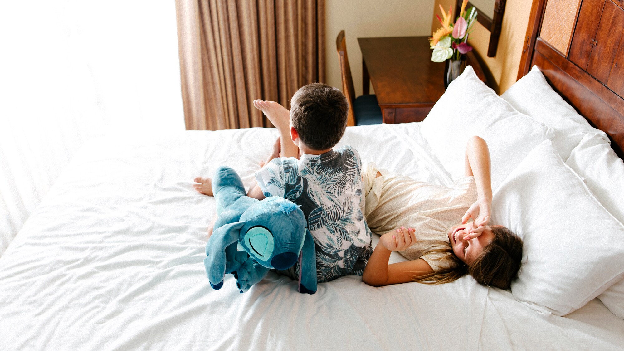 Two children lounging on a hotel bed