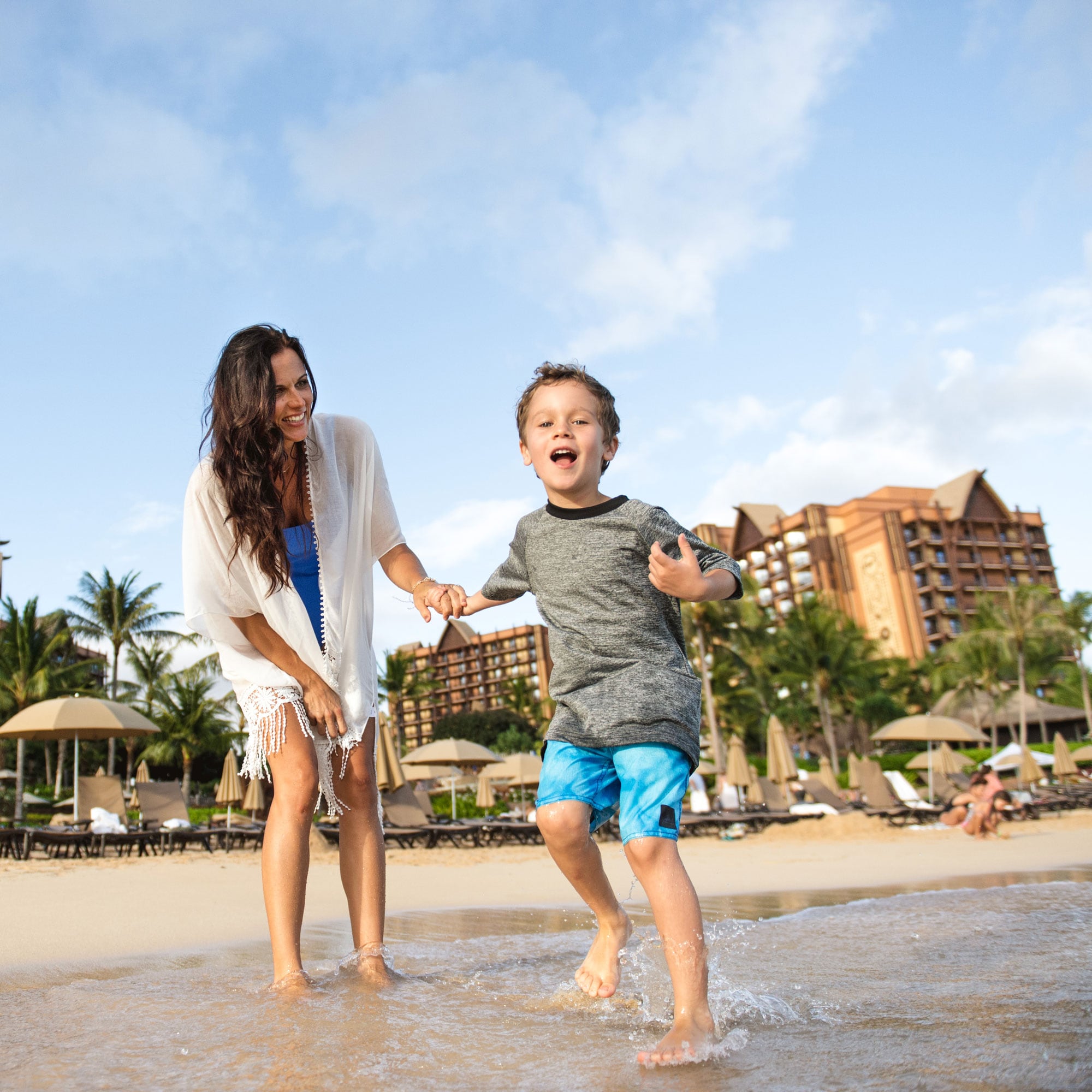 Mother and son on beach with Aulani in the background