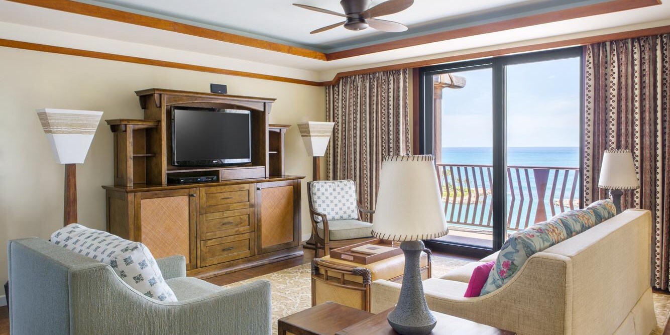 A living room with a sliding glass door that opens to a balcony overlooking the ocean