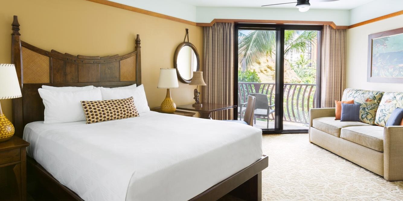 A bedroom with a sofa and a sliding glass door that opens to a balcony