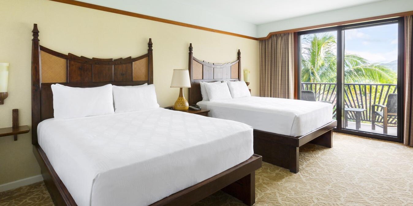 A bedroom with 2 beds and a sliding glass door that opens to a balcony