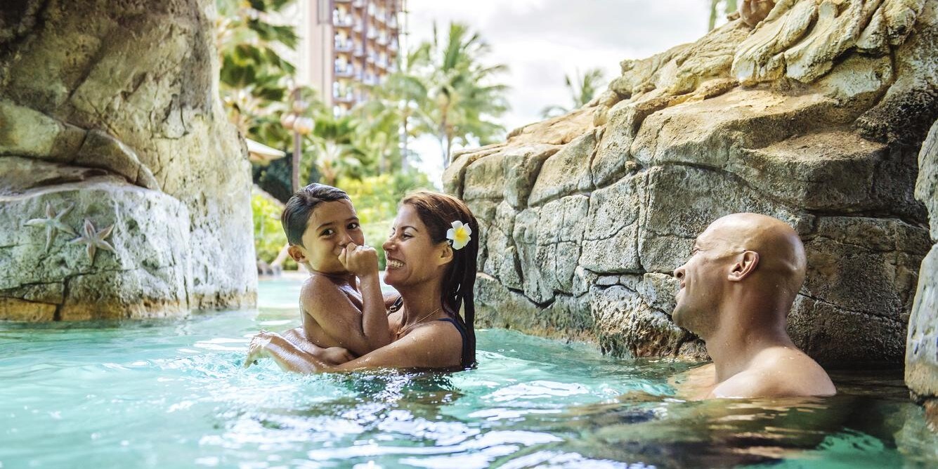A man, woman and their son relaxing together in a swimming pool