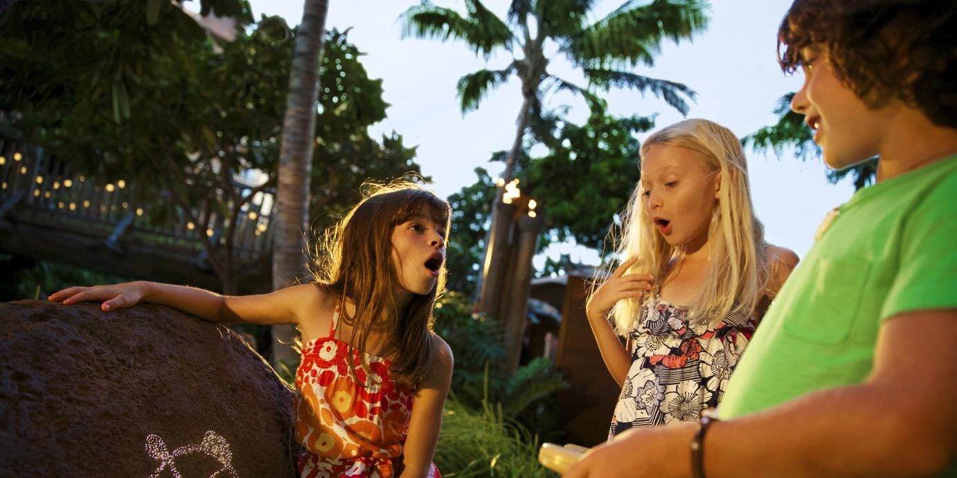 Two girls and a boy gathered around a boulder decorated with a turtle drawing