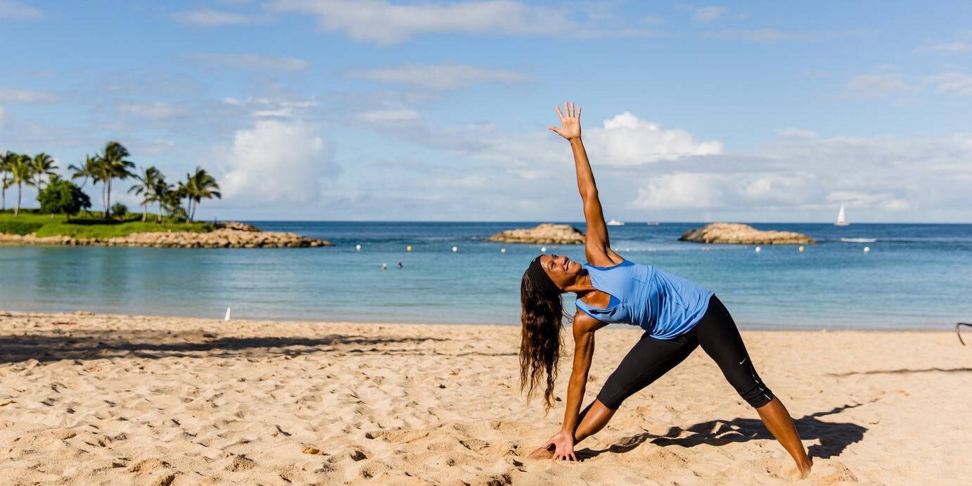 A woman practicing yoga on the beach