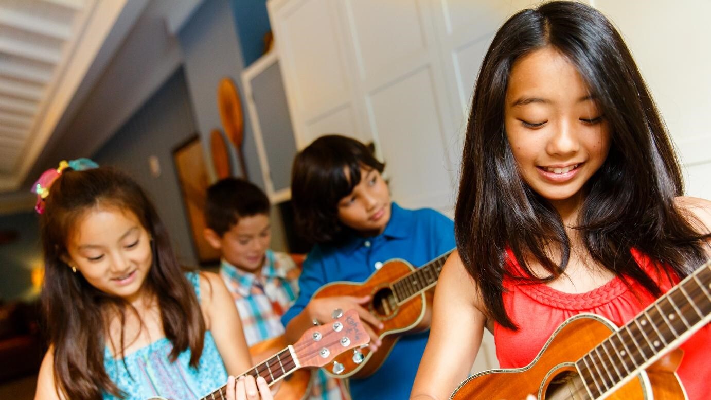 4 children strumming ukeleles