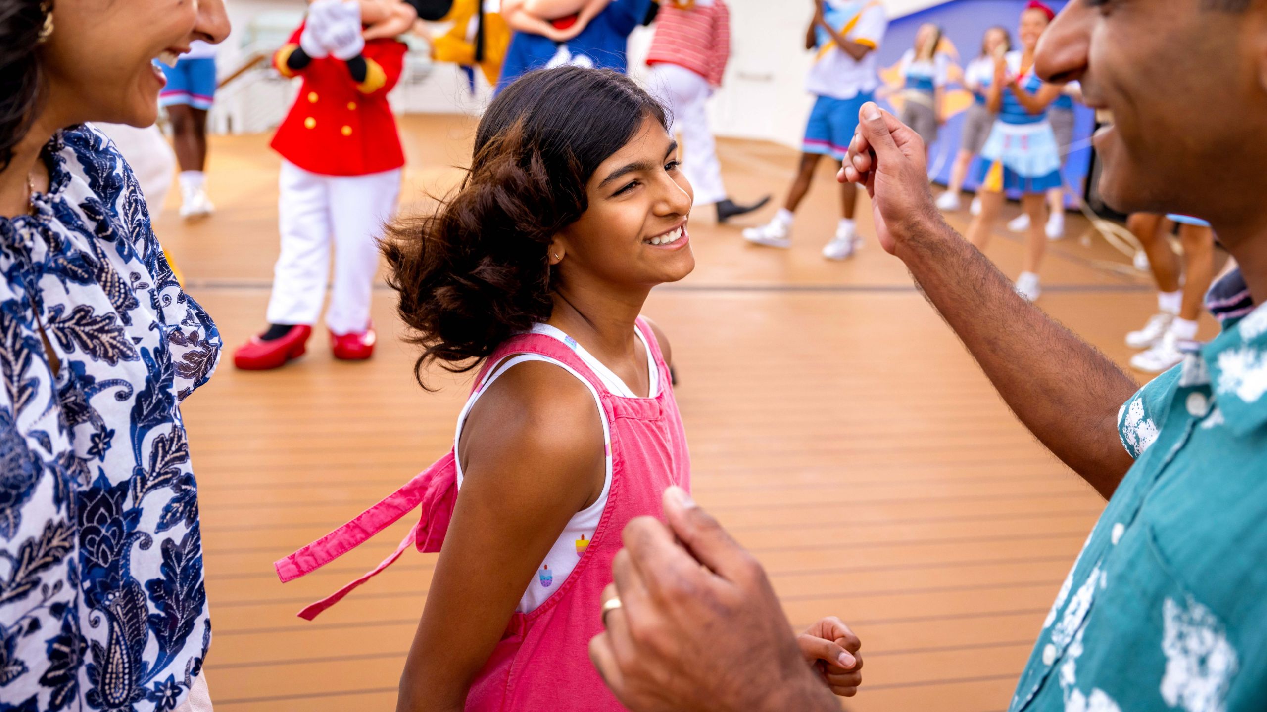 Two parents and their teenage daughter dancing in front of Captains Mickey Mouse and Minnie Mouse