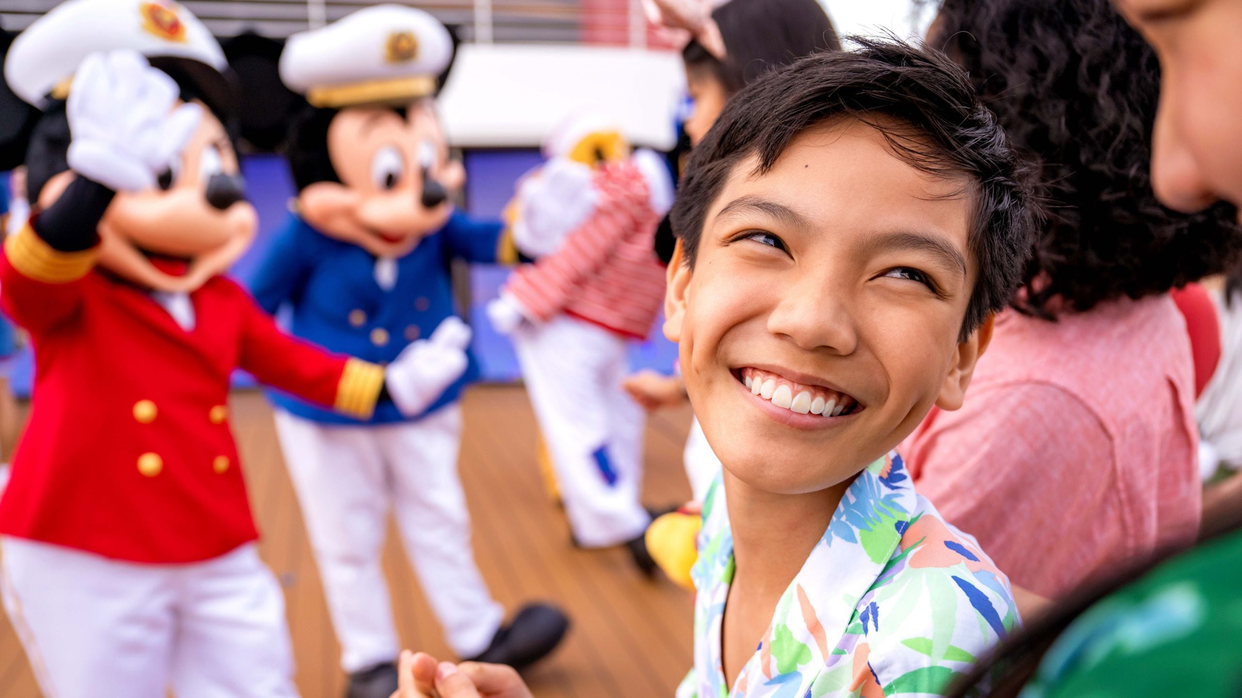 A young boy smiling in front of Captains Mickey Mouse and Minnie Mouse