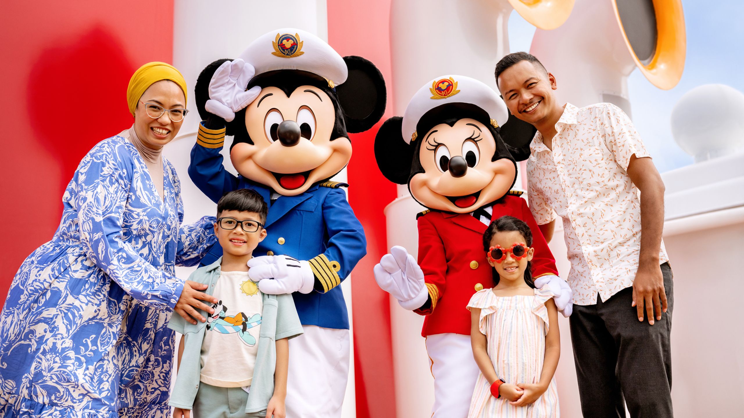 Captains Mickey Mouse and Minnie Mouse pose with a family of 4 on a Disney Cruise Line ship 