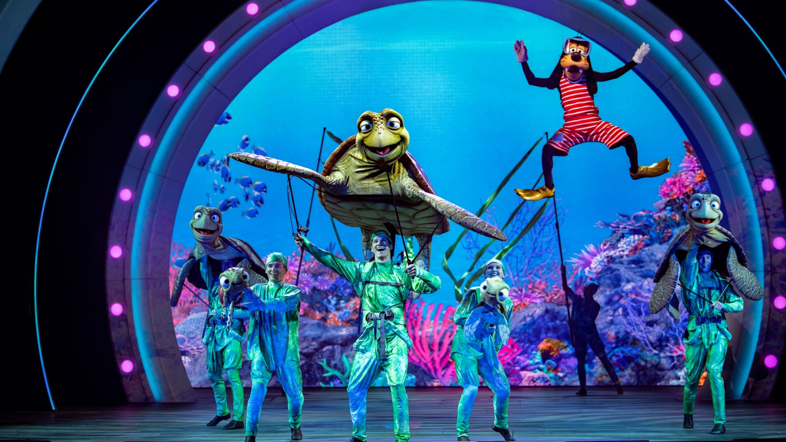 A Finding Nemo stage show with sea turtle puppets and Goofy