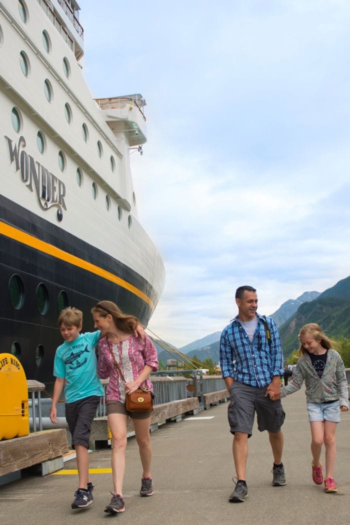 A family walking on a dock next to the Disney Wonder cruise ship