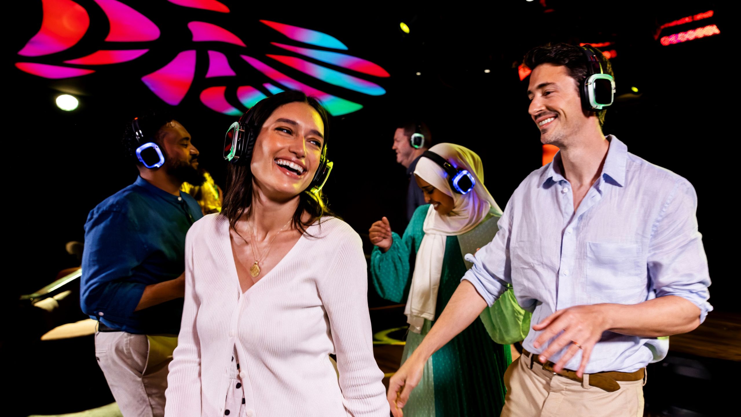Guests wearing light up headphones and dancing at a disco party with lights overhead