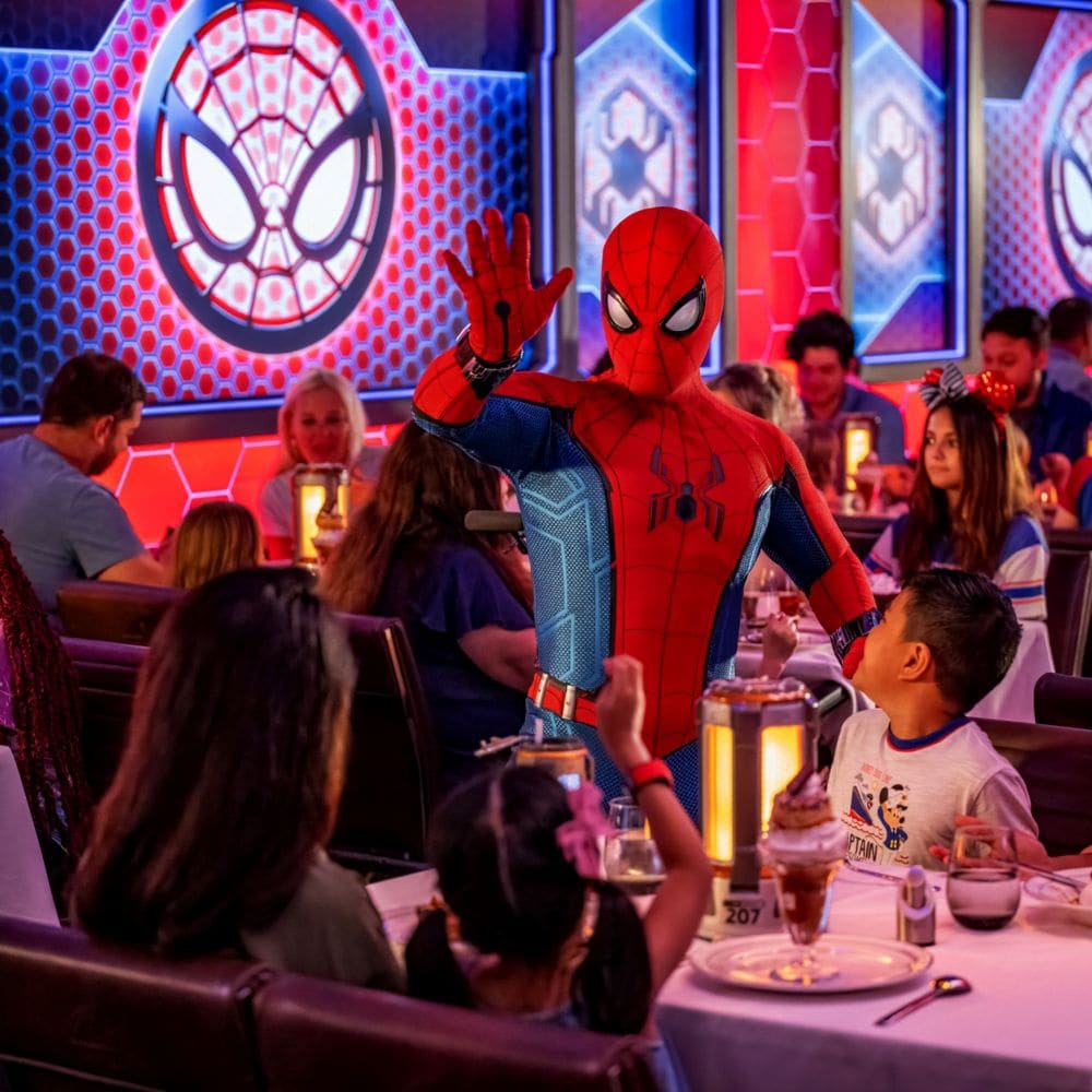 Spider Man interacting with excited children at Worlds of Marvel