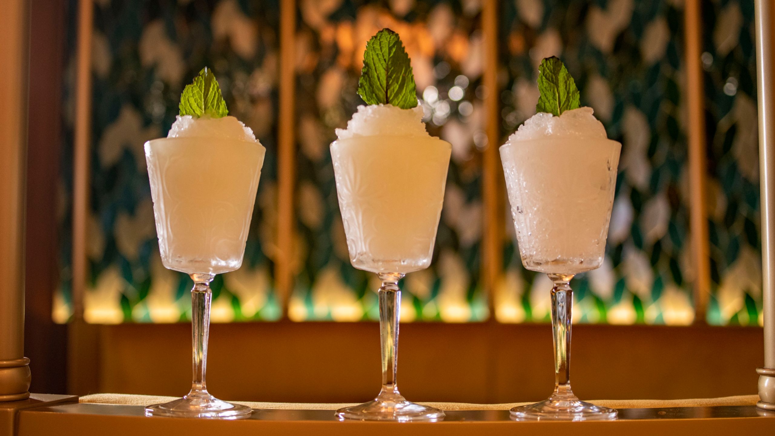 Three Absinthe Frappes from The Bayou in elegant glasses, garnished with mint leaves and arranged in a row