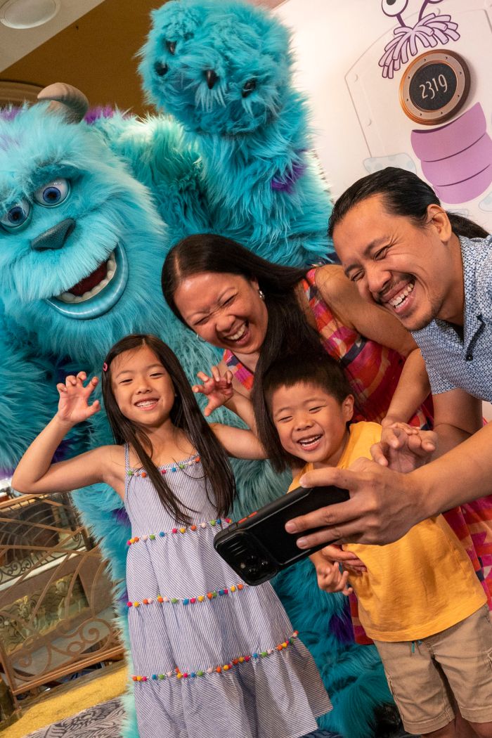 A family of 4 posing with Sulley from ′Monsters Inc.′