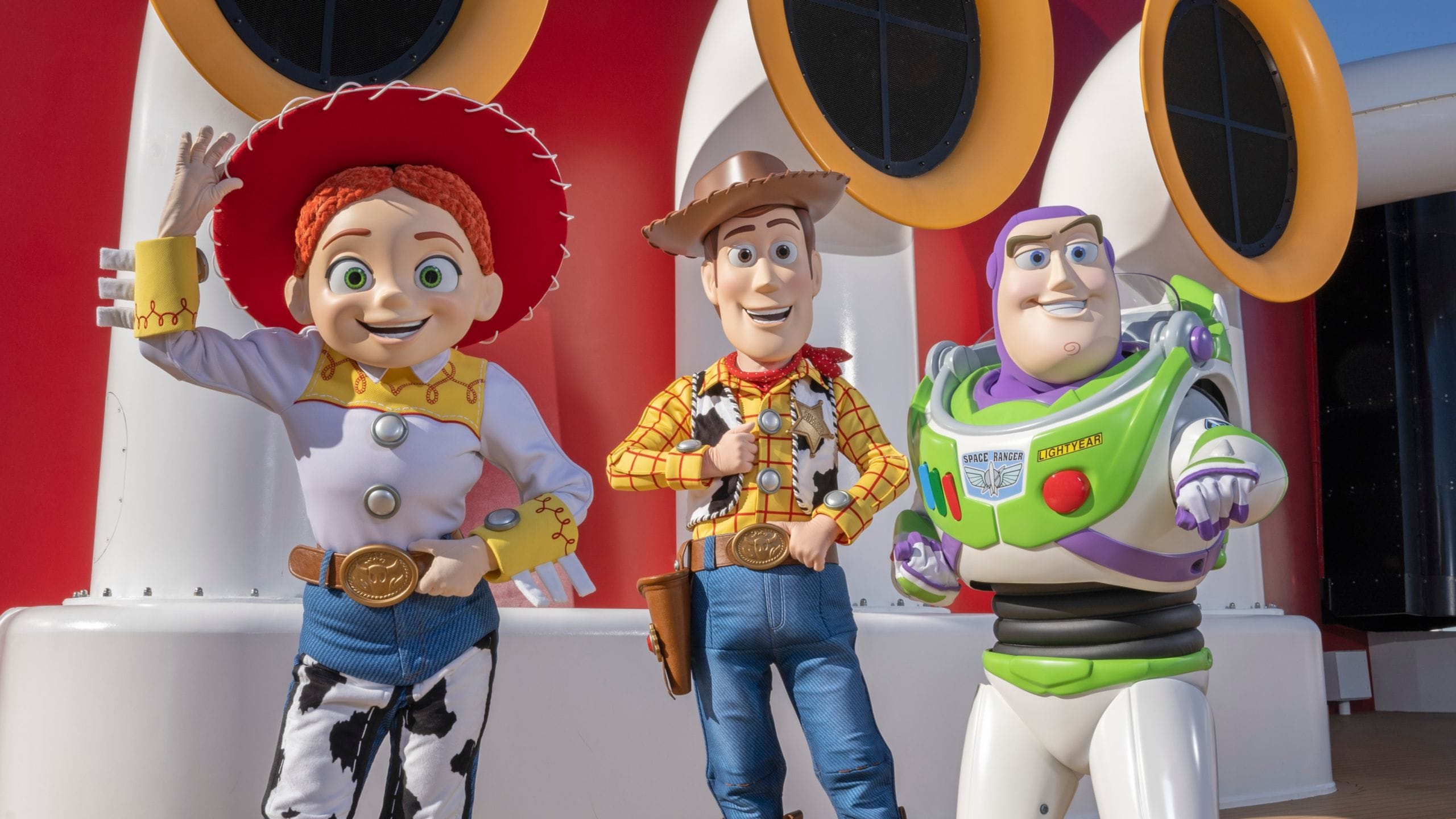 Toy Story characters Jessie, Woody and Buzz Lightyear standing on the deck of a Disney Cruise Line ship 