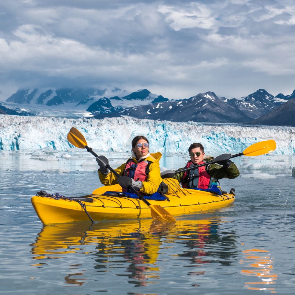 Guests paddling a 2 person kayak in waters off a glacier in Alaska
