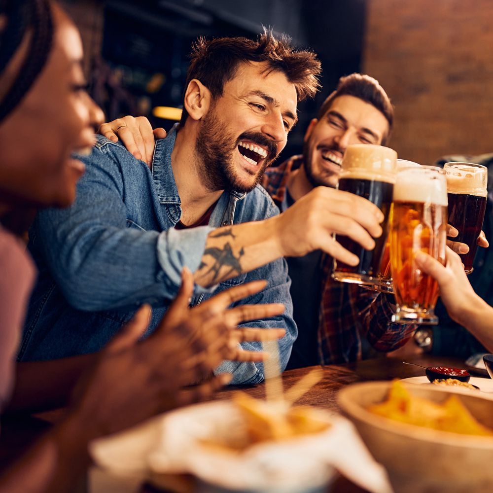 A table of smiling Guests toasting beers together