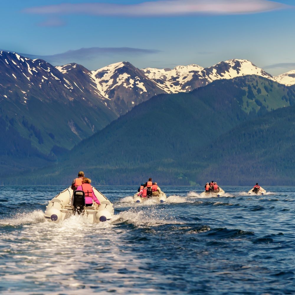 Guests traveling in a group of rubber inflatable boats in the waters near Skagway, Alaska