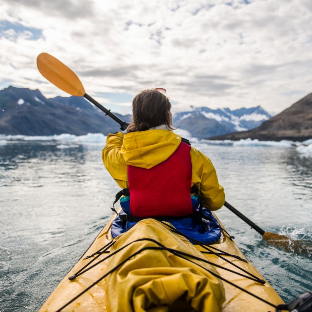 A Guest paddling a kayak throw a bay in Sitka, Alaska