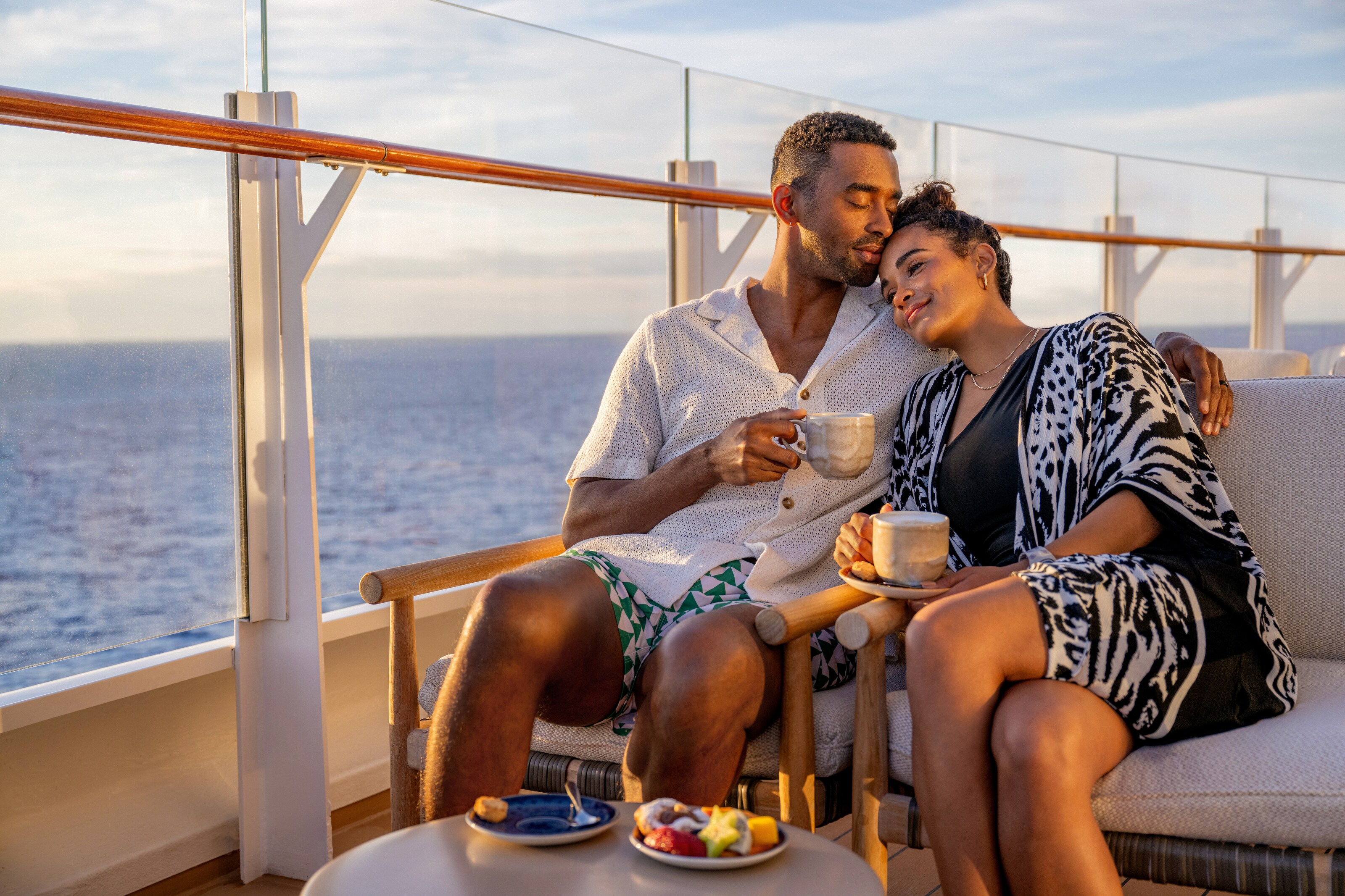Una pareja acurrucada y disfrutando de bebidas calientes en la cubierta de un barco de Disney Cruise Line