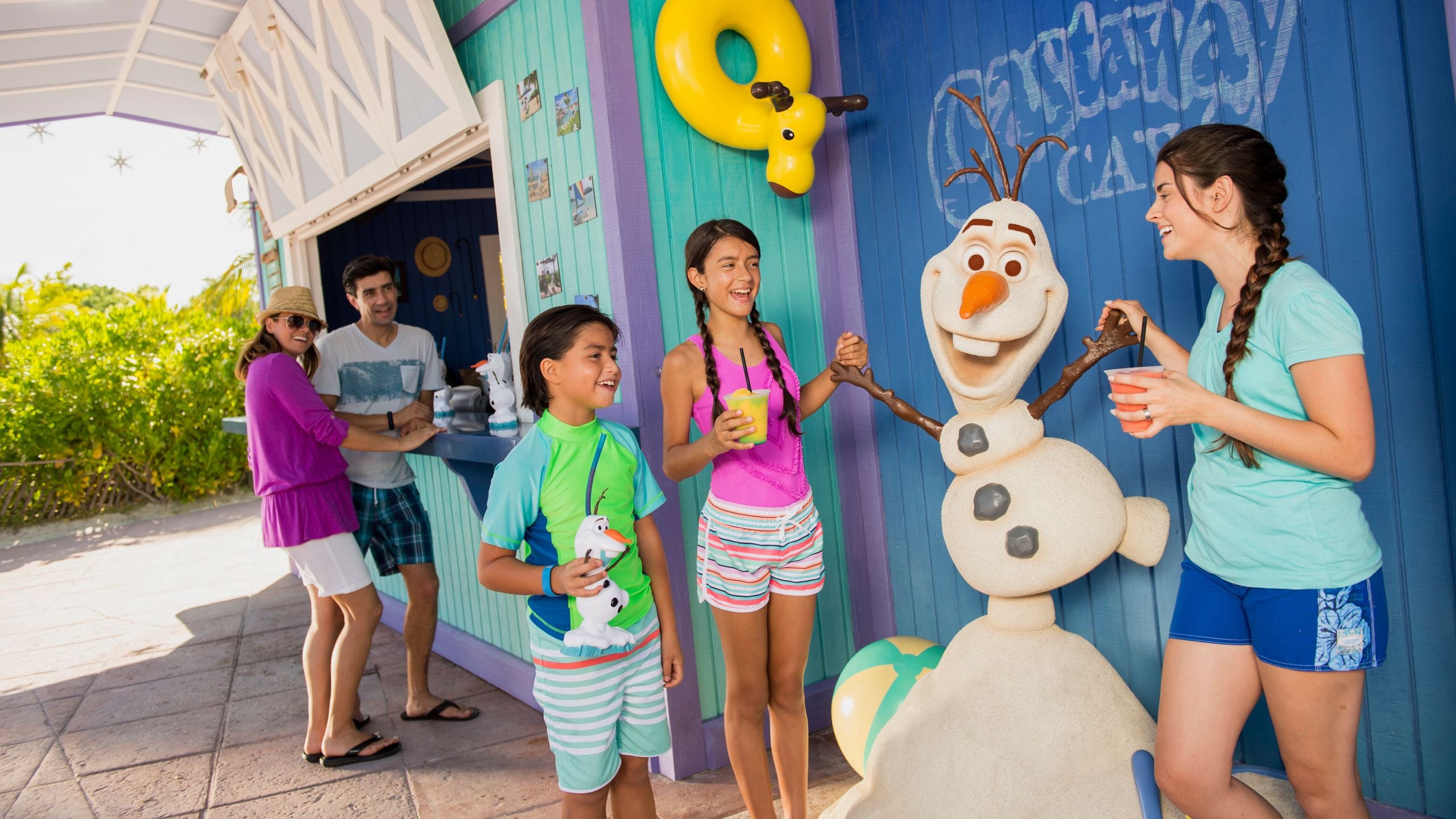 Children interacting with a statue of Olaf outside of the Disney Castaway Cay Summertime Freeze stand and 2 adults observing 