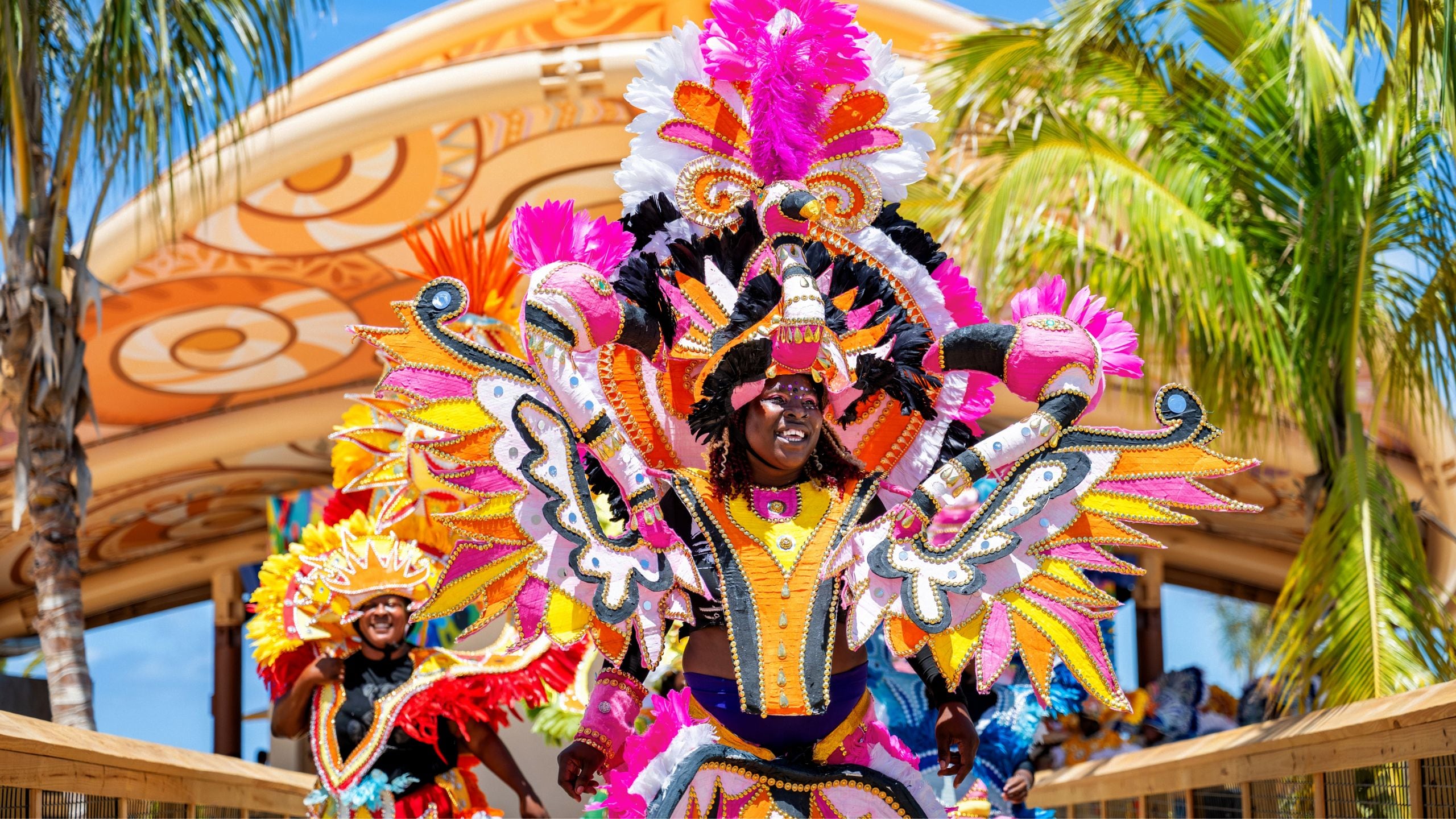 Una mujer sonriendo y bailando en un desfile mientras viste ropa festiva bahameña.
