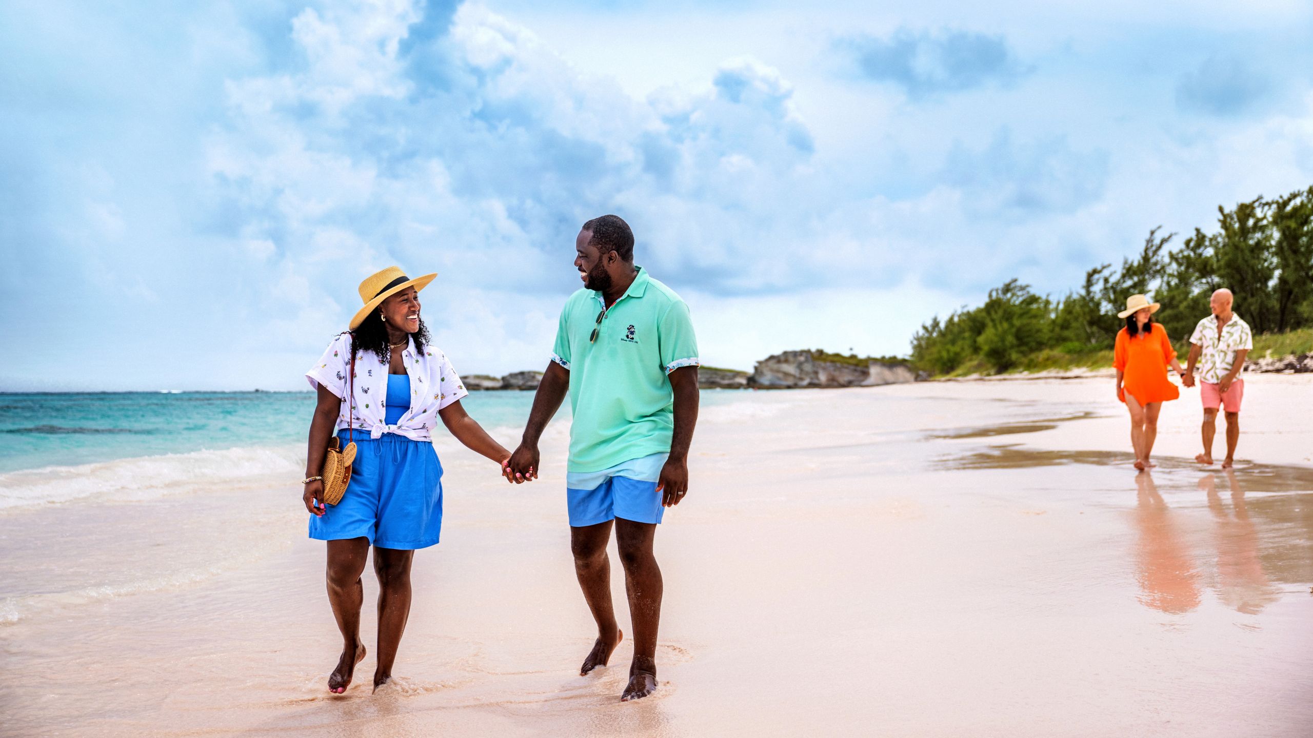 Dos parejas tomadas de la mano mientras caminan por una playa