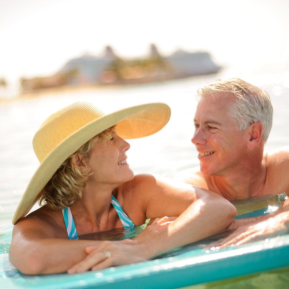 Una mujer y un hombre se miran con amor a los ojos mientras nadan en el agua.