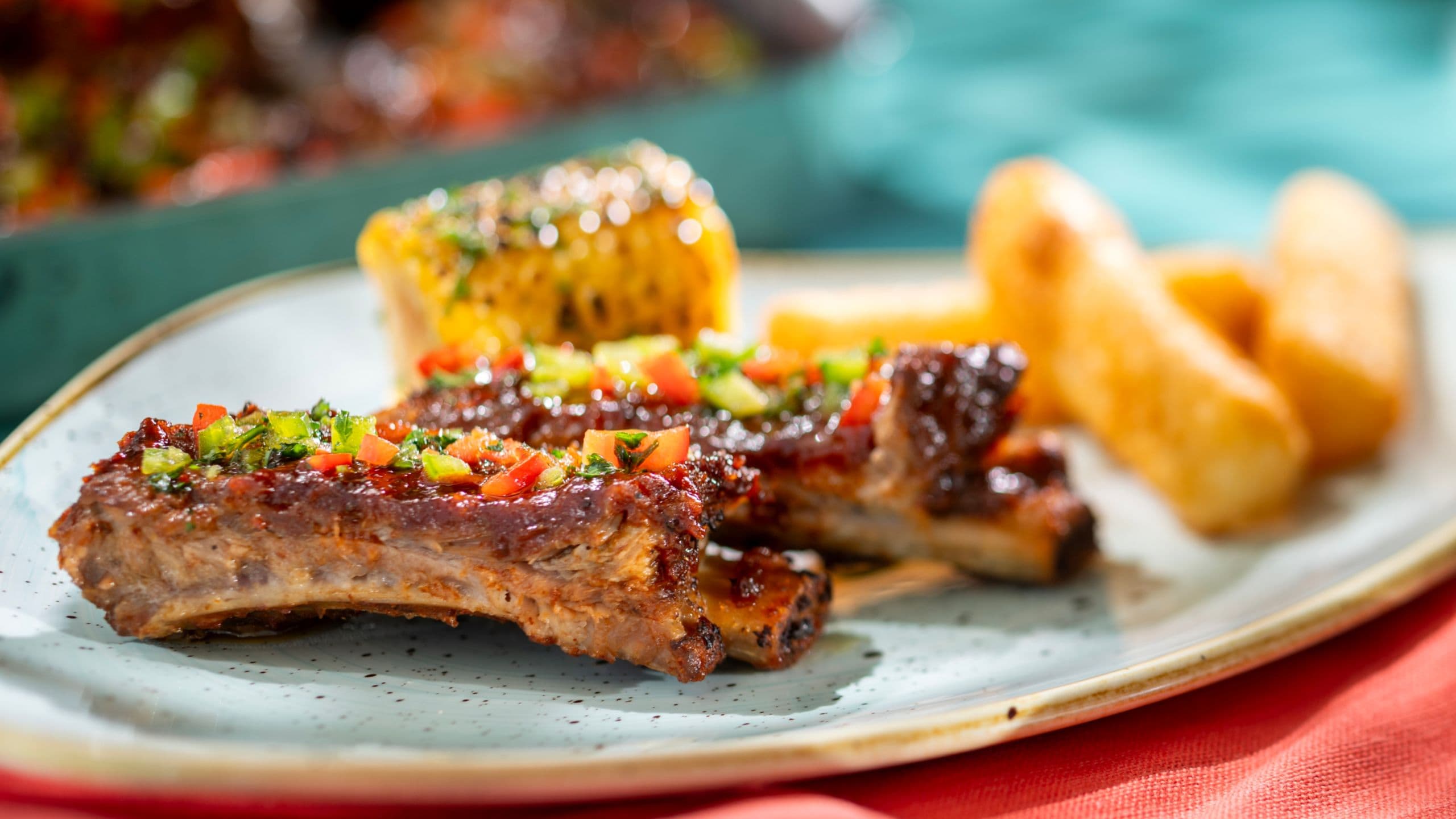 Un plato de costillas a la barbacoa, mazorcas de elote y palitos de mozzarella fritos
