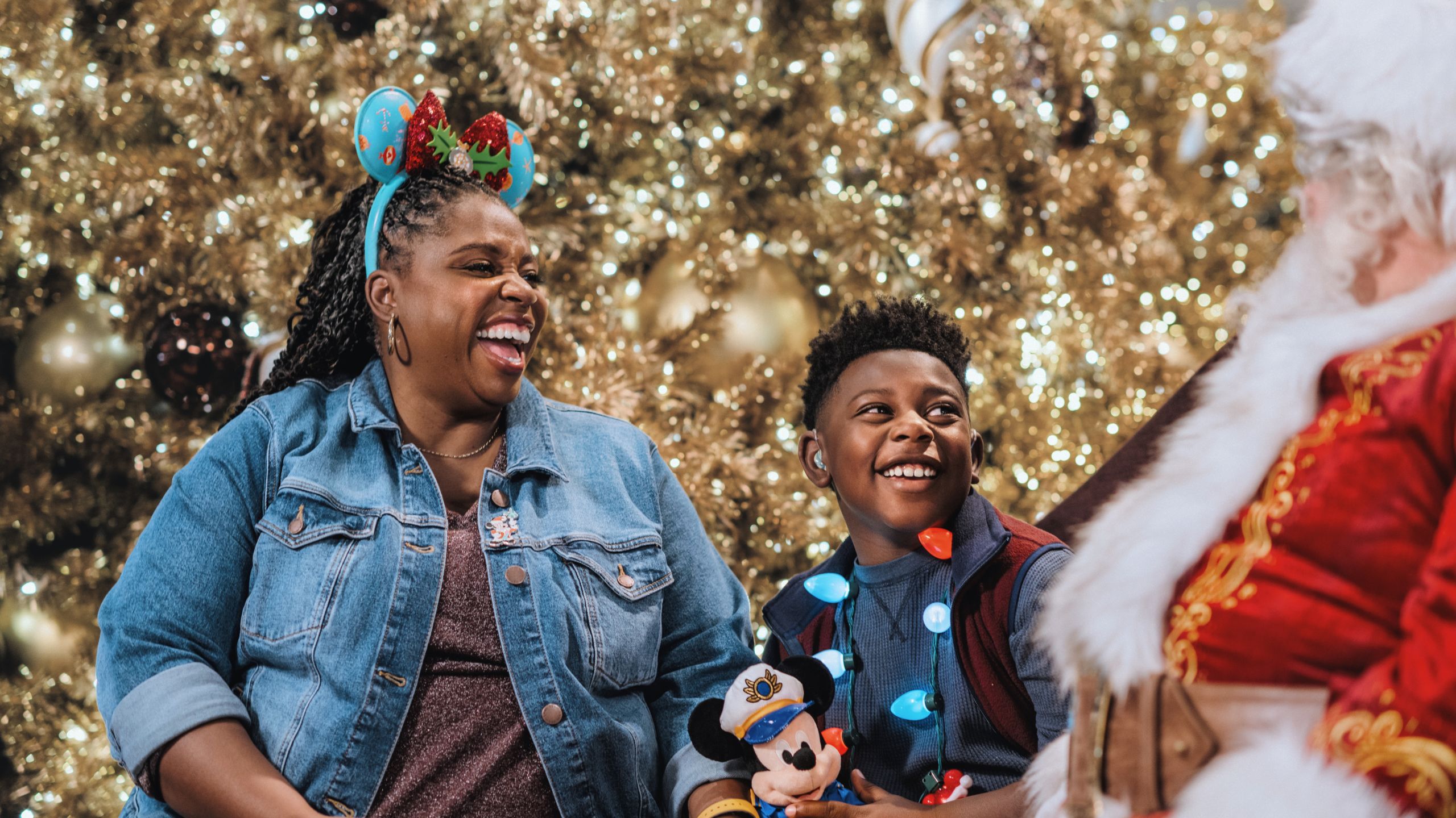 A mother and her young son sharing a laugh with Santa Claus
