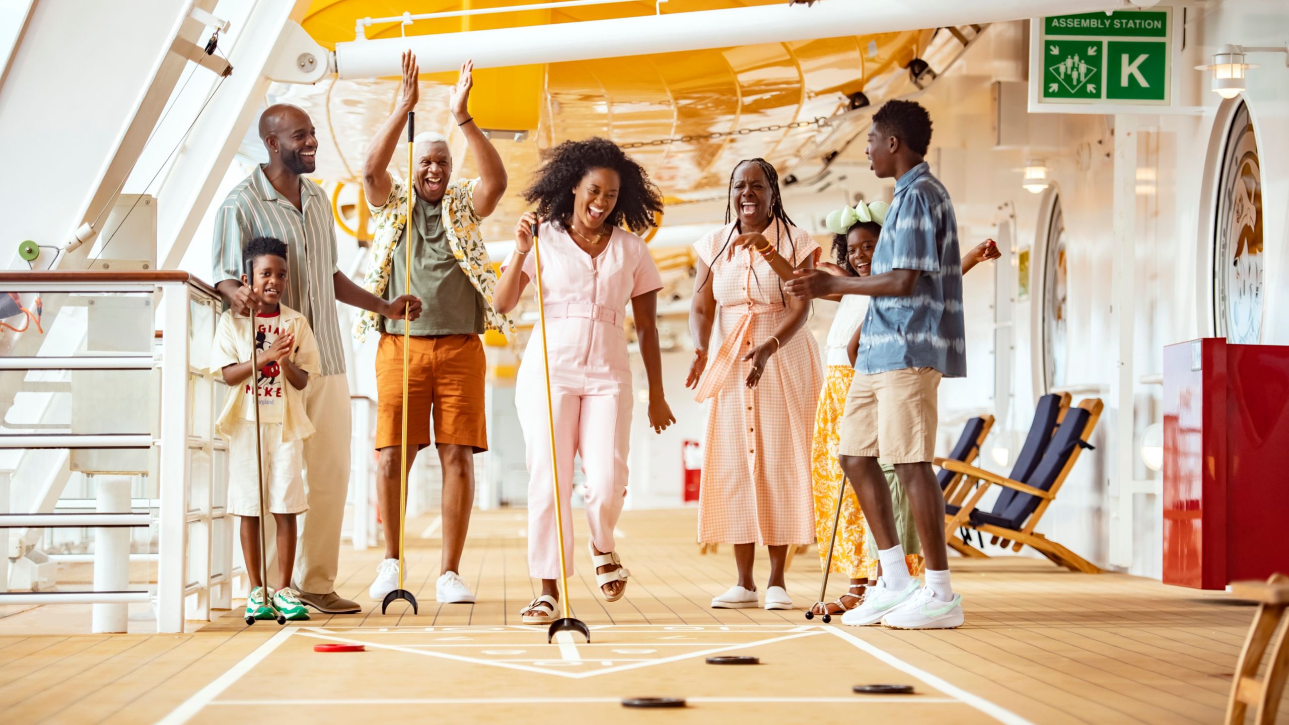A family of 7 enjoying a game of shuffleboard on a Disney Cruise Line ship
