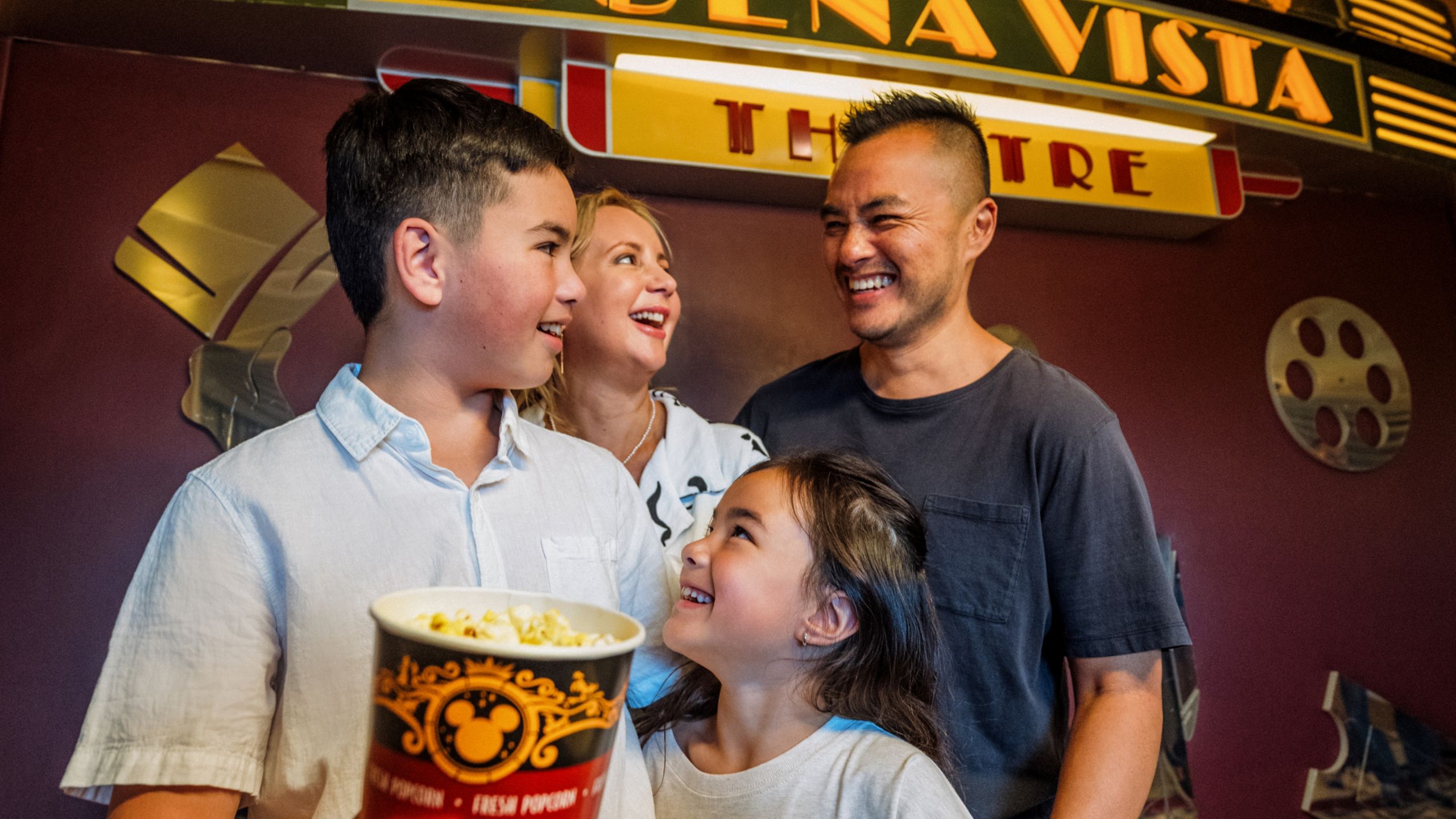 A smiling family holding a tub of popcorn by Buena Vista Theatre 