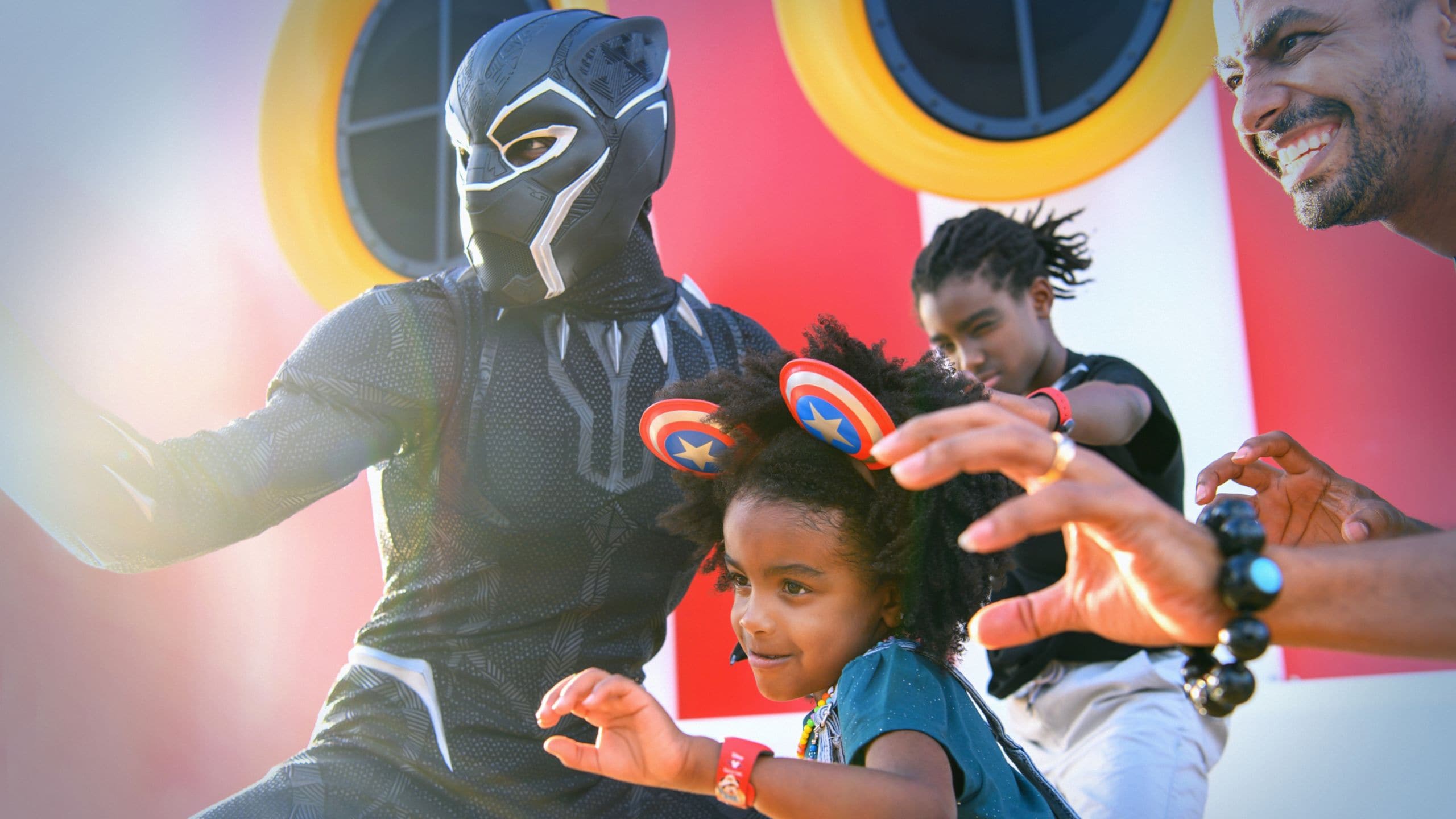 Uma família sorri e posa em posição de luta com o Pantera Negra