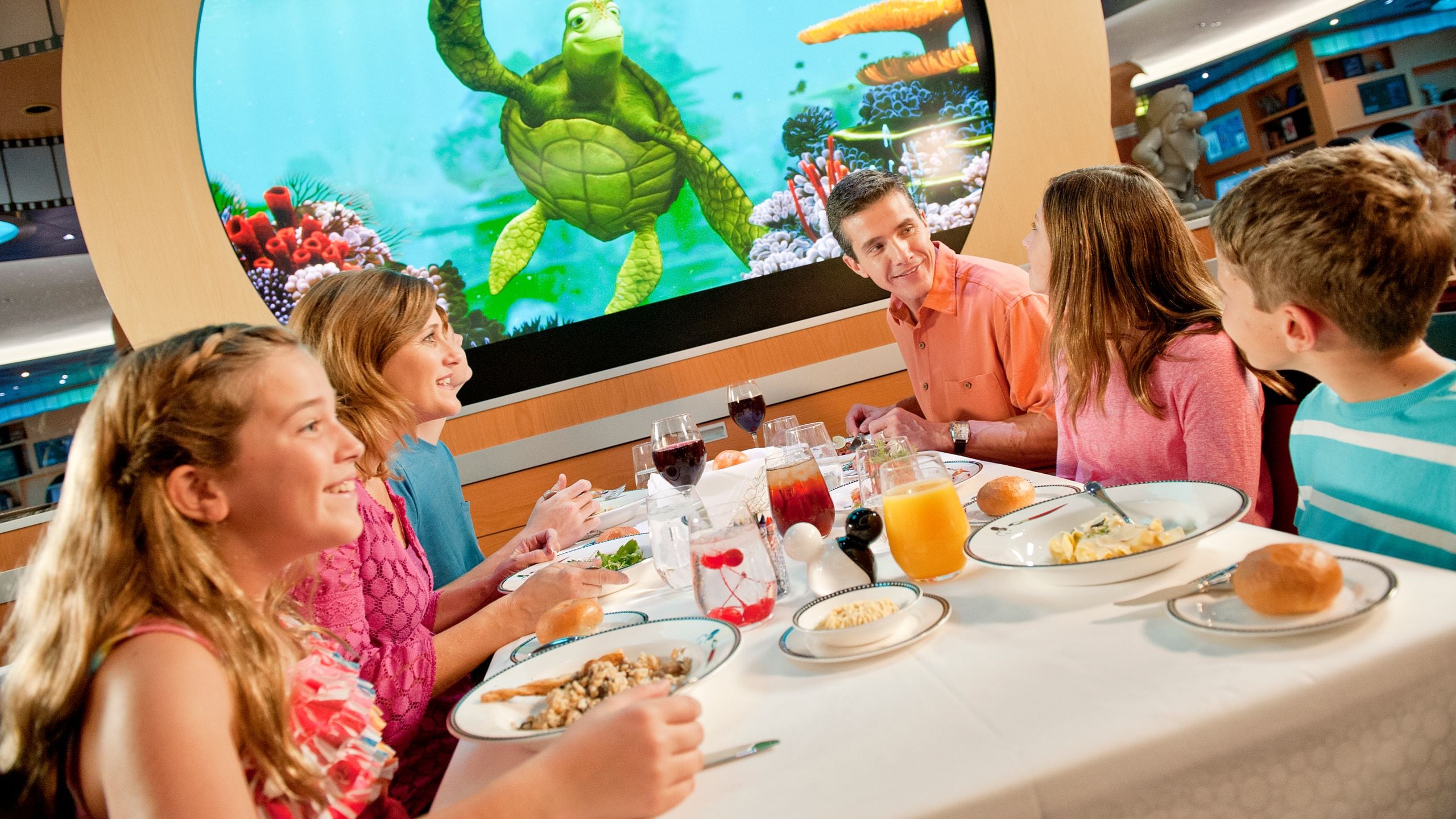 Uma família sorri enquanto saboreia uma refeição com Crush no Animator's Palate a bordo do navio de cruzeiro Disney Dream