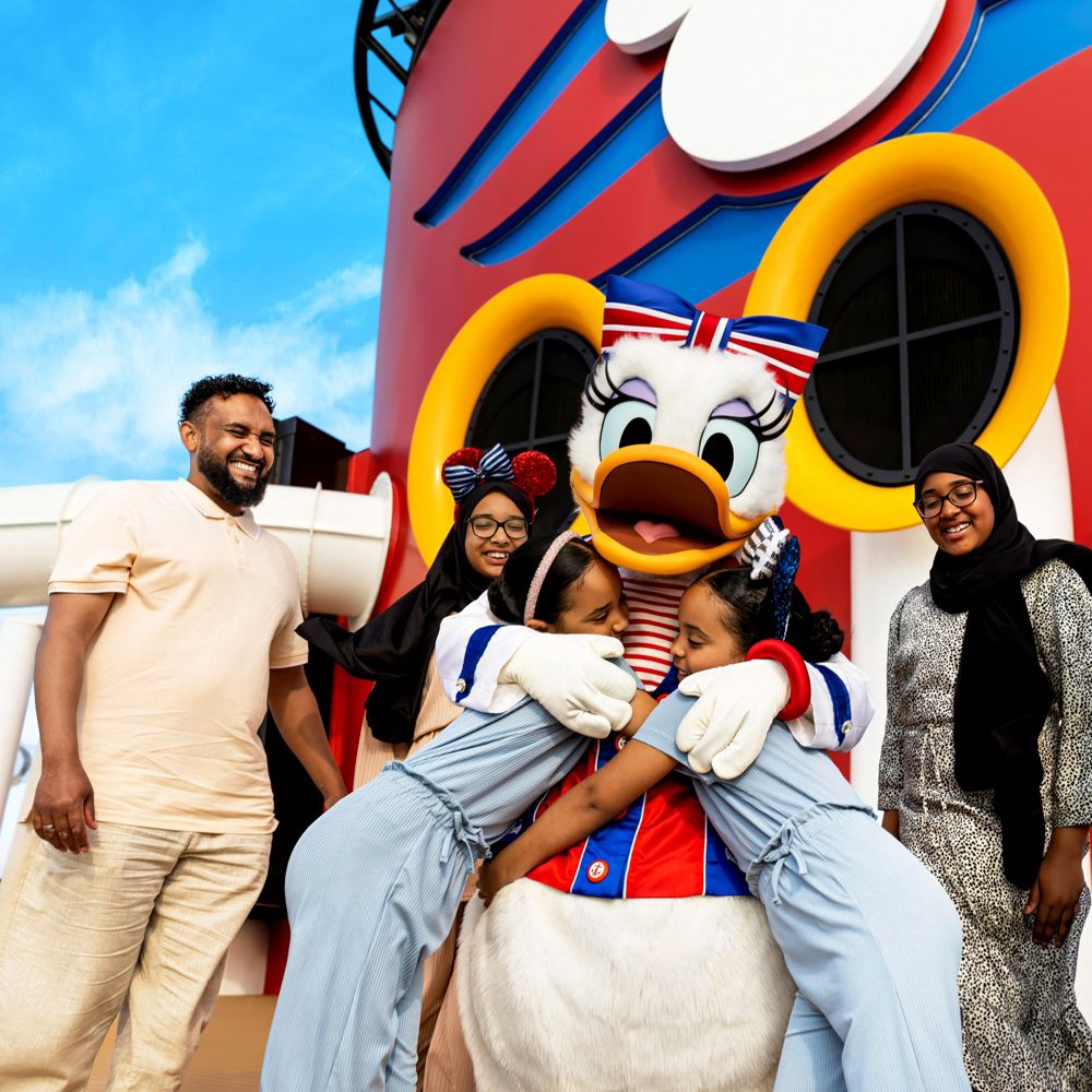 Uma família sorri e abraça Margarida a bordo do navio Disney Fantasy