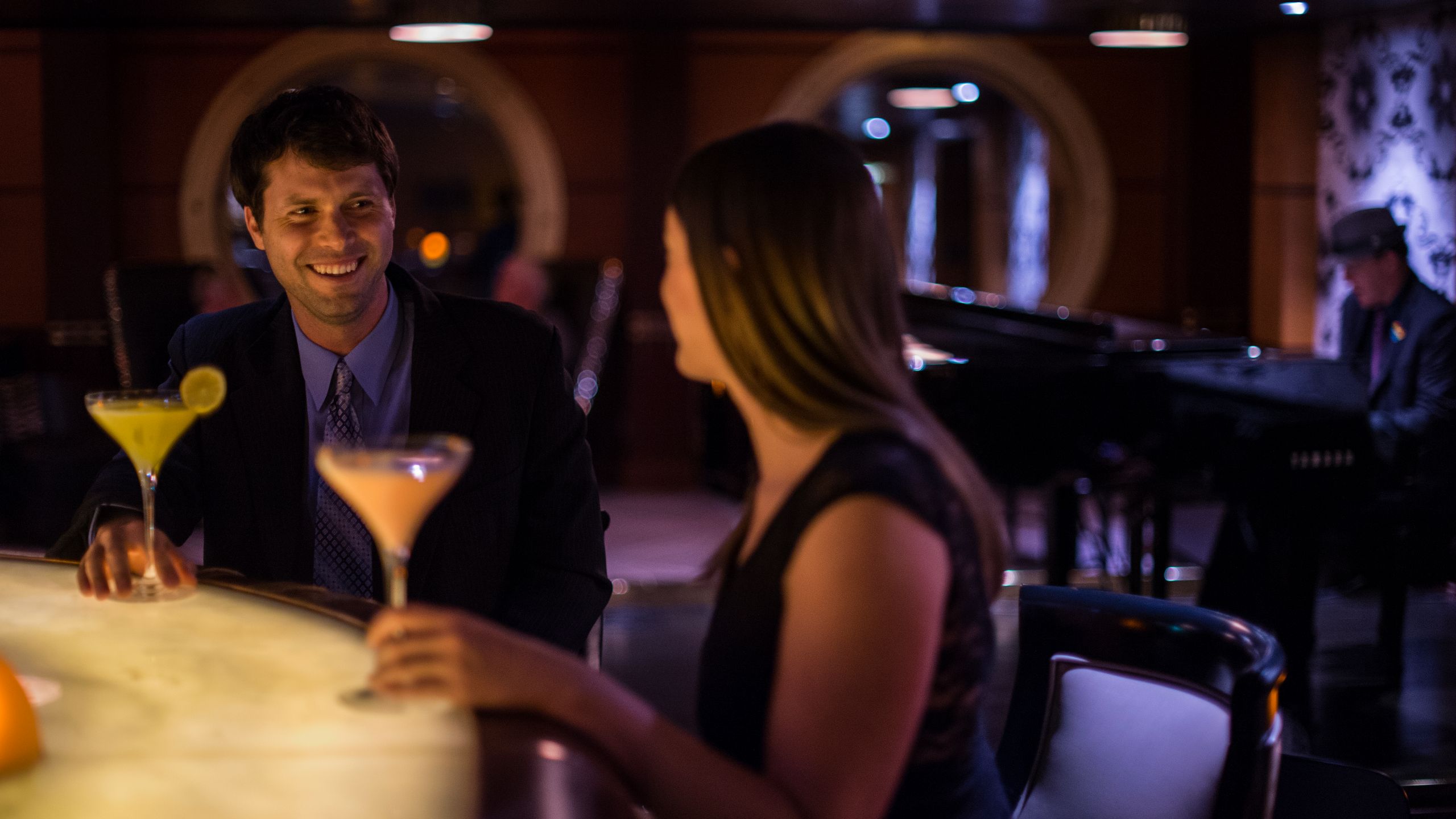 A man and a woman drinking cocktails in a bar