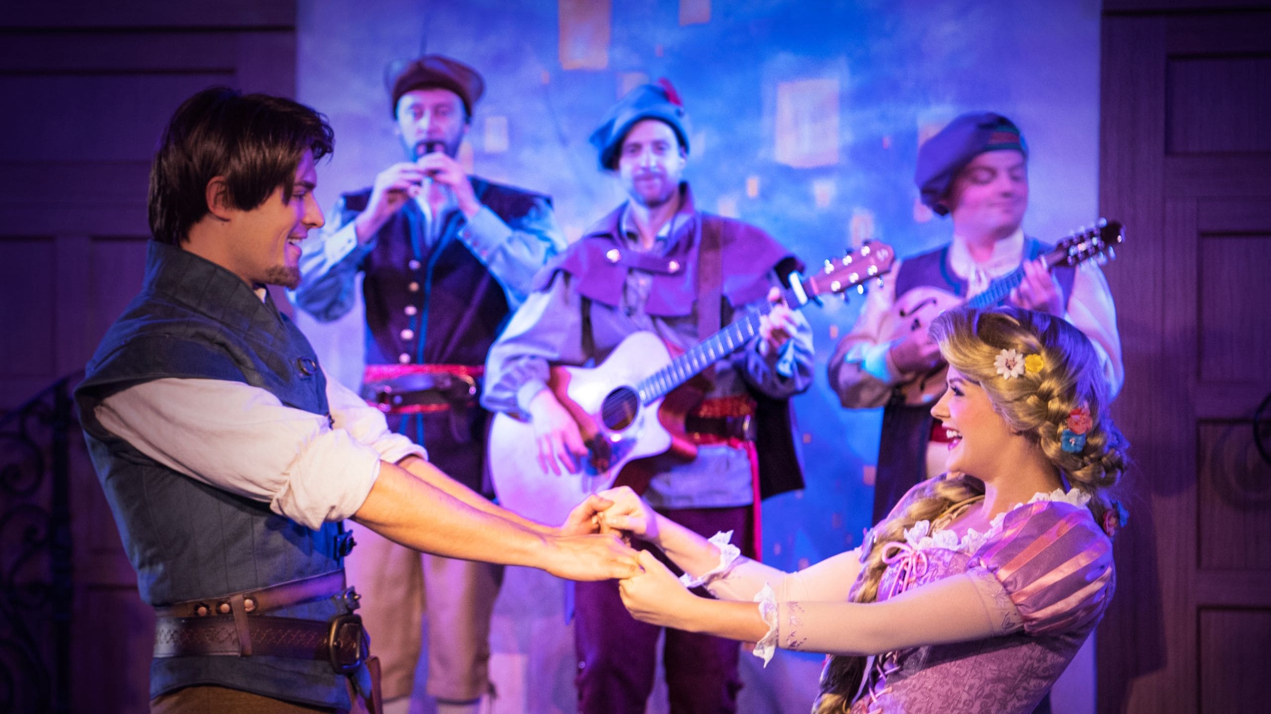 Rapunzel e Flynn Rider de mãos dadas no palco da Rapunzel's Royal Table