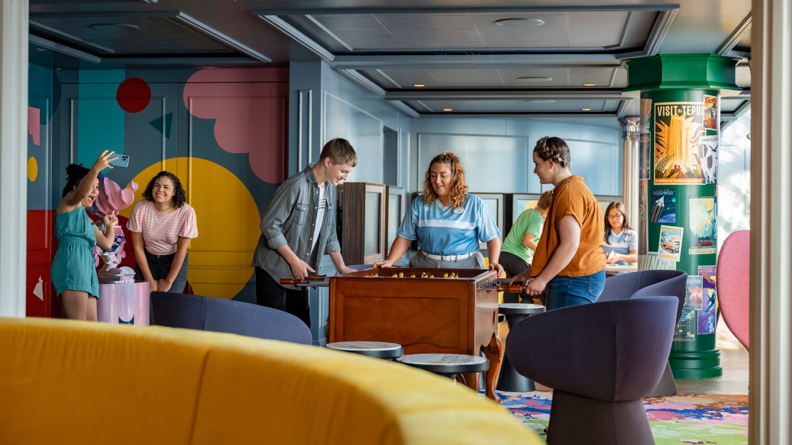 A group of teens playing foosball at the Vibe loft on board the Disney Destiny ship