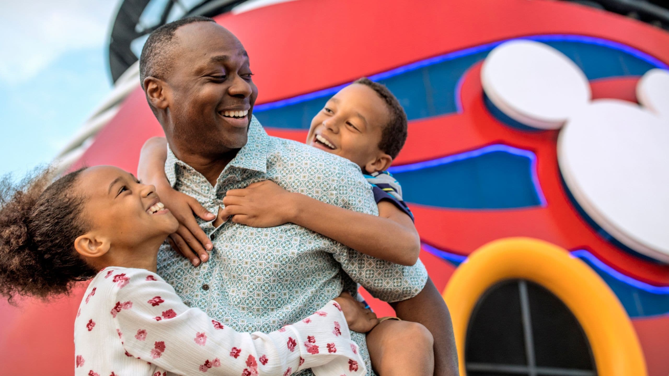 Um pai carrega seu filho nas costas enquanto sua filha o abraça a bordo de um navio da Disney Cruise Line