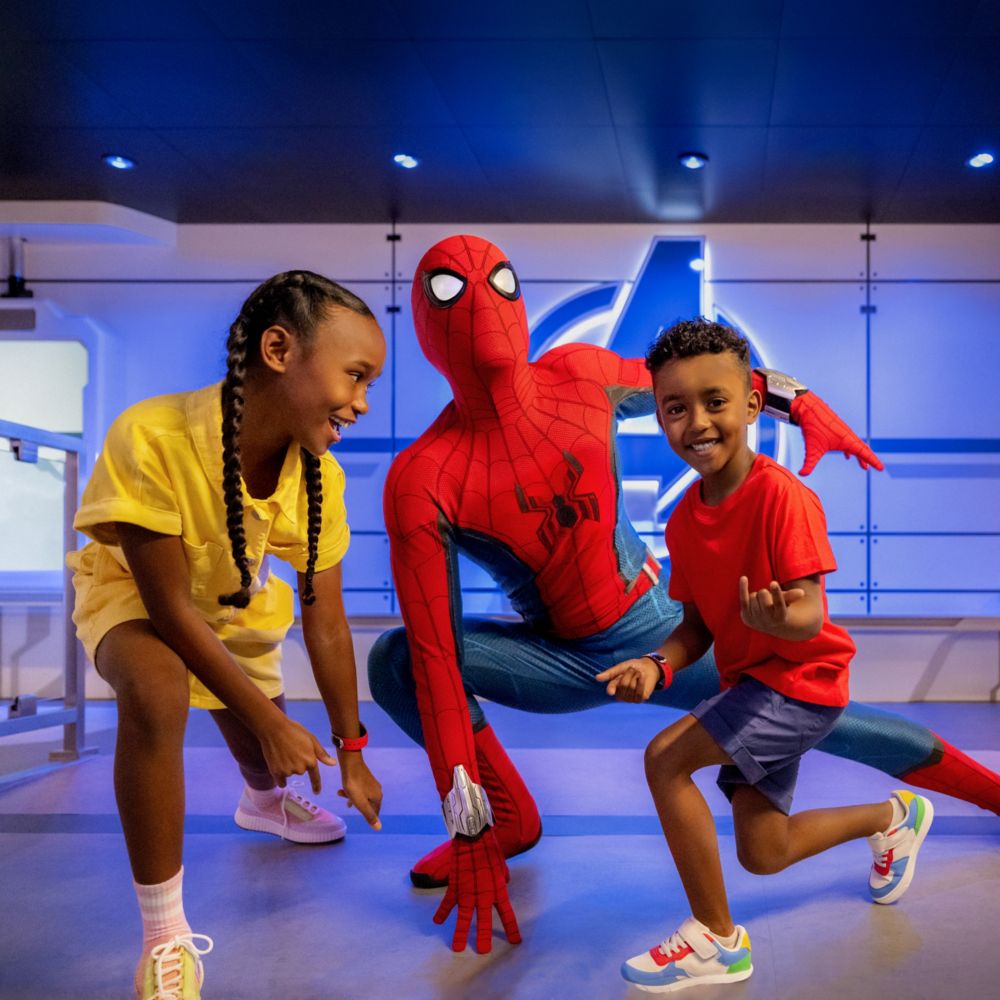 Two children smile and pose with Spider Man