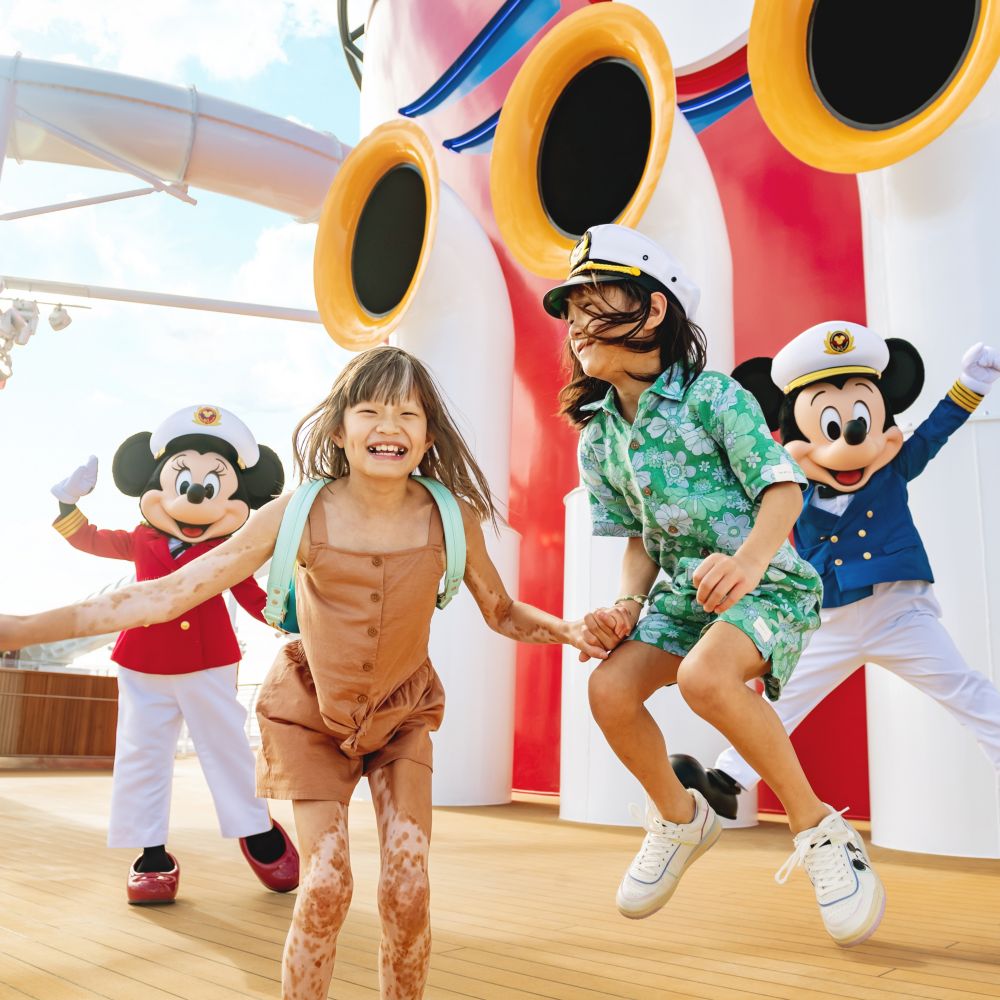 Crianças pulam no ar com os capitães Minnie Mouse e Mickey Mouse no deck do navio de cruzeiro Disney Wish